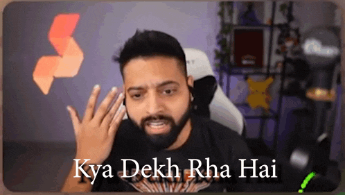 a man with a beard is making a funny face in front of a camera with the words kya dekh rha hai on the bottom