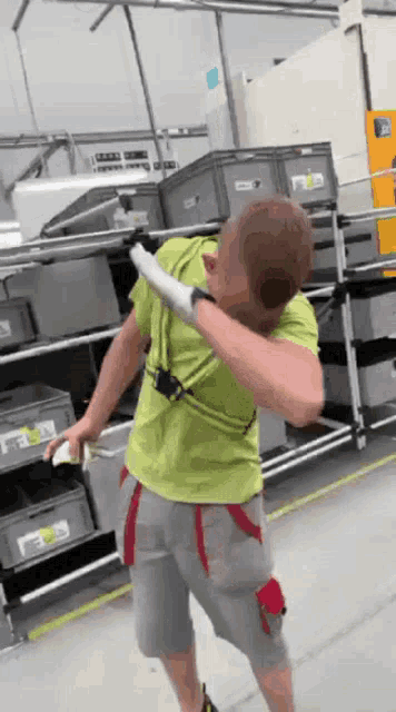 a man wearing a green shirt and grey shorts is doing a dab