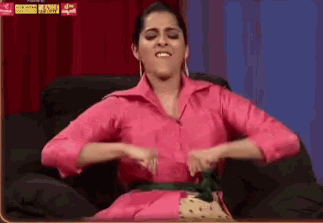 a woman in a pink shirt is sitting in a chair with her hands on her stomach .