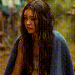a woman with long dark hair is wrapped in a blue blanket
