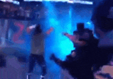 a blurry picture of a person dancing in front of a blue light with the number 22 on the wall behind them