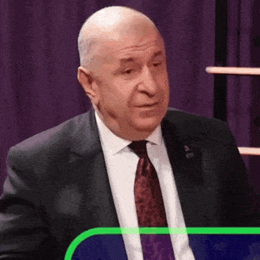 a man in a suit and tie is sitting in front of a purple background