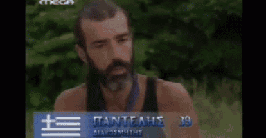 a man with a beard is wearing a black tank top and a blue and white flag around his neck .