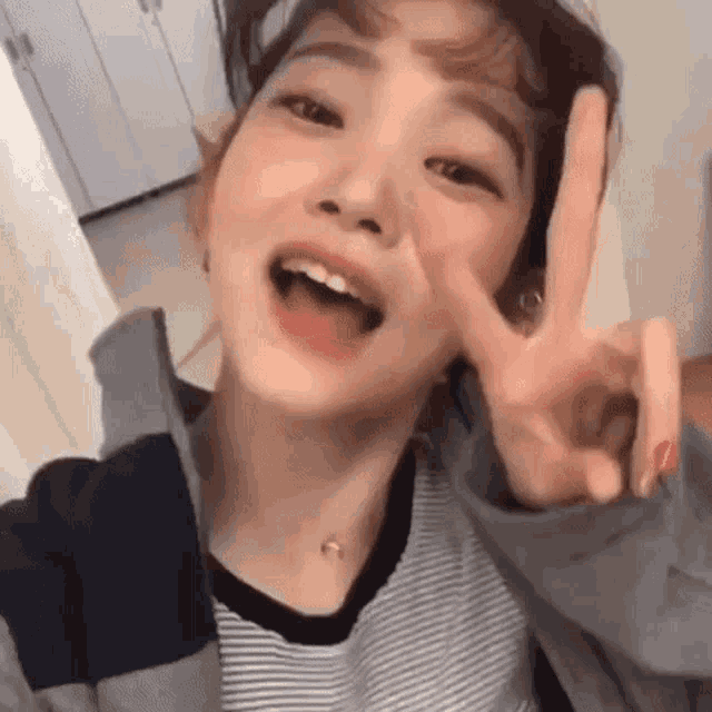 a young woman is making a peace sign with her hand .