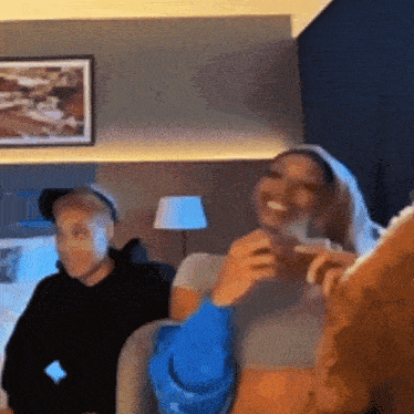a man and a woman are sitting on a couch in a room laughing .
