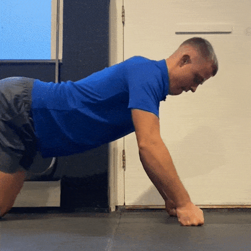 a man in a blue shirt and shorts is doing push ups
