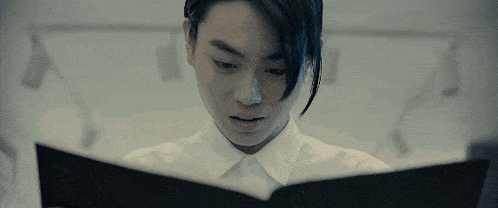 a young man is reading a book in a dark room .