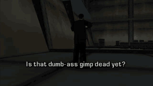 a man standing in a dark room with the words is that dumb-ass gimp dead yet written below him