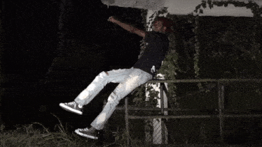a person sitting on a railing with their feet in the air and a black shirt that says ' supreme ' on it