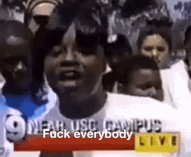 a group of people are standing in front of a sign that says " near usc campus fuck everybody "