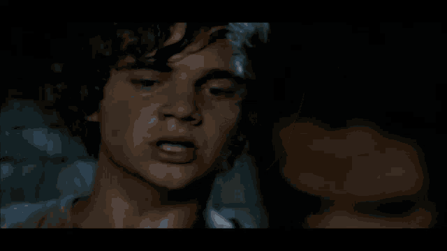a close up of a man 's face with a woman 's face in the background