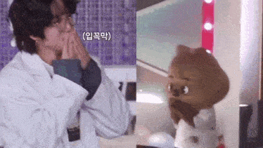 a man in a lab coat is standing next to a stuffed animal and covering his mouth .
