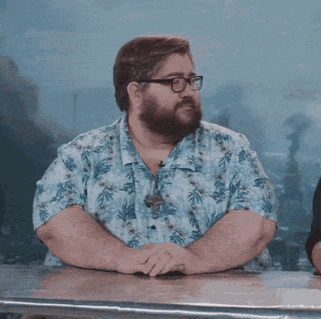 a man with glasses and a beard sits at a table