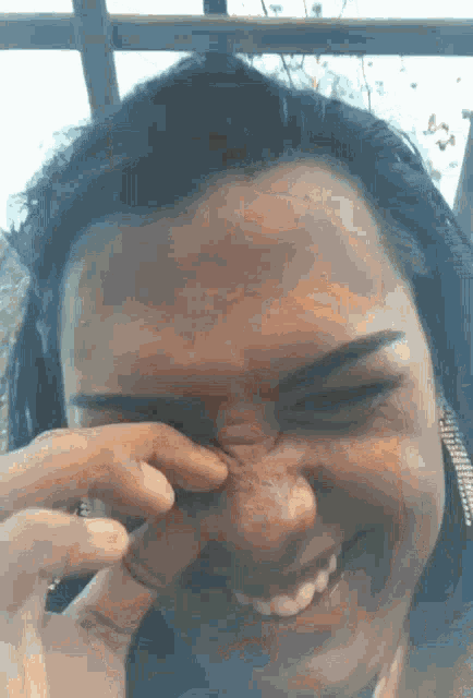 a close up of a woman 's face with a hand holding her nose