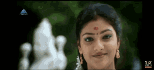 a woman with a red dot on her forehead is smiling for the camera