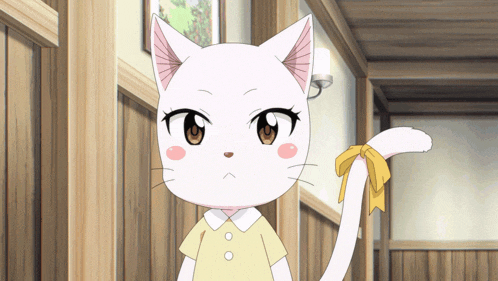 a white cat with a yellow bow on its tail stands in a hallway