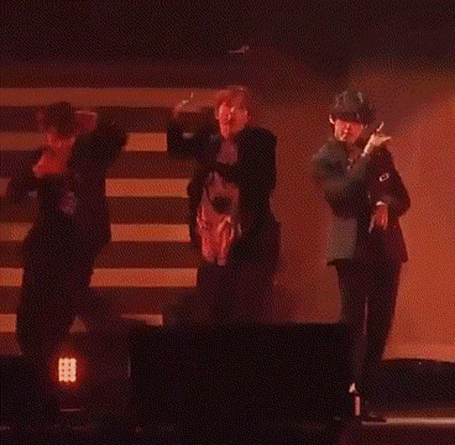 a man in a supreme shirt is dancing on a stage with other men .