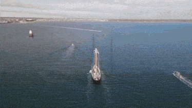 an aerial view of a sailboat in the middle of the ocean