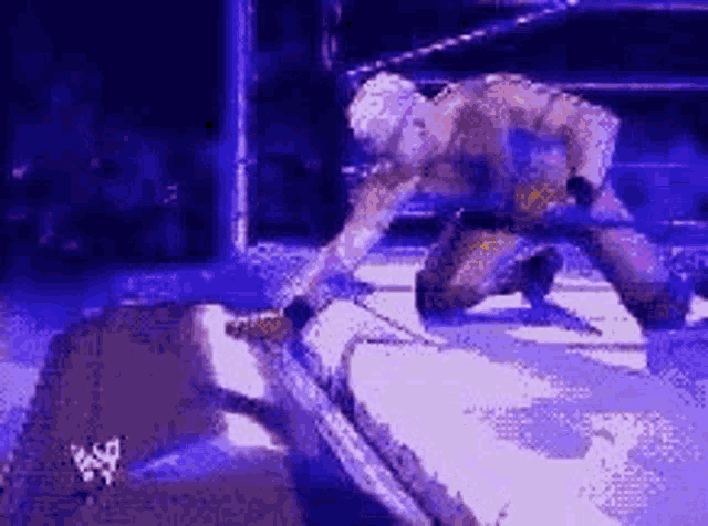 a wrestler is kneeling down in a wrestling ring with a rope .