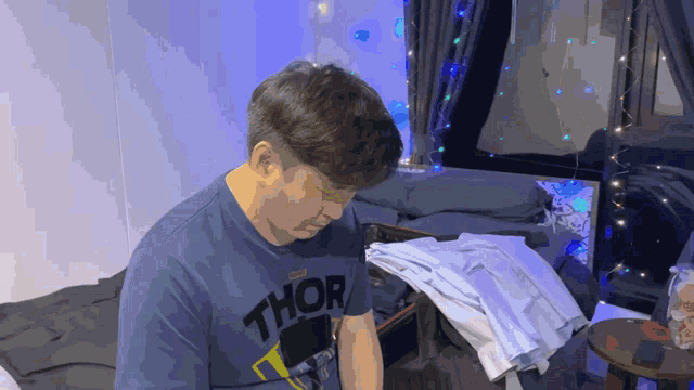 a man wearing a shirt that says thor looks down