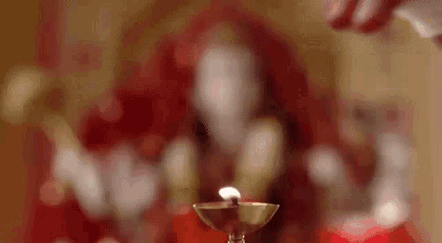 a close up of a person lighting a candle in front of a statue .