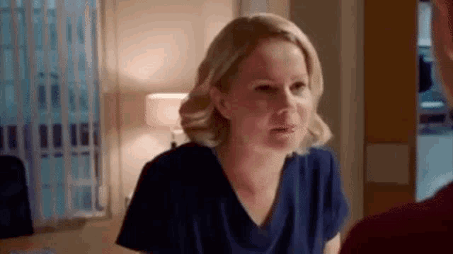 a woman in scrubs is talking to a man in a room .