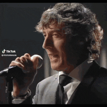a man in a suit and tie is singing into a microphone