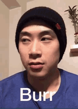 a man wearing a black beanie and a blue shirt is making a funny face and saying burr .