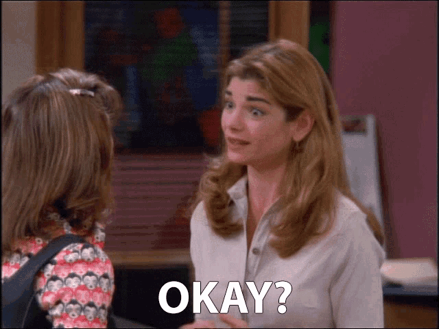 a woman talking to another woman with okay written on the bottom right