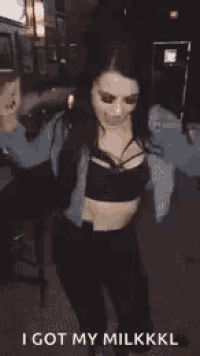 a woman in a crop top and a denim jacket is dancing in the street .