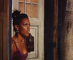 a woman in a purple tank top stands in front of a white door