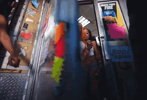 a woman standing in front of a door with a sign that says " drinks your fire "