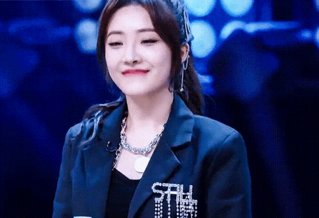 a woman wearing a blue jacket and a necklace with the word ctrl on it