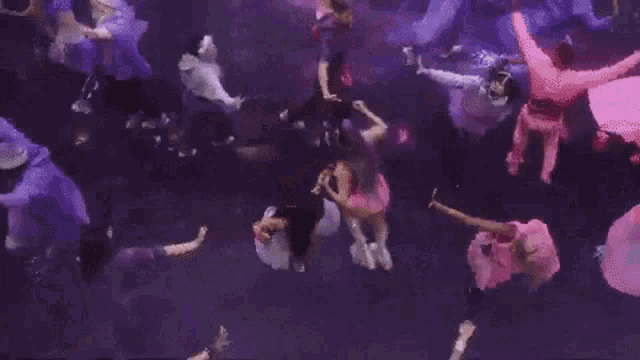 a group of people are dancing underwater in a purple room .