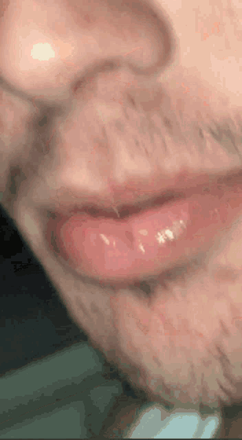 a close up of a man 's mouth with a beard and a tongue sticking out .