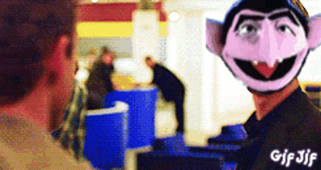 a gif of a man wearing a sesame street character 's mask