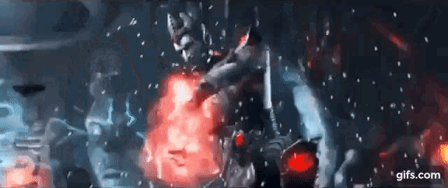 a man is holding a sword in a dark room with a red light behind him .
