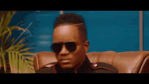 a man wearing sunglasses and a military uniform is sitting on a couch .