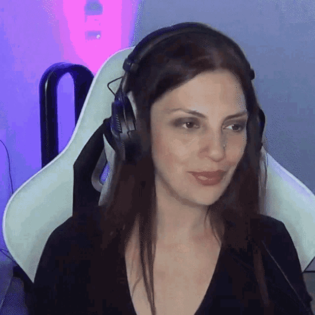 a woman wearing headphones is sitting in a chair and smiling