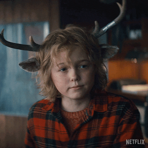 a young boy with antlers on his head is wearing a plaid shirt with netflix written on the bottom