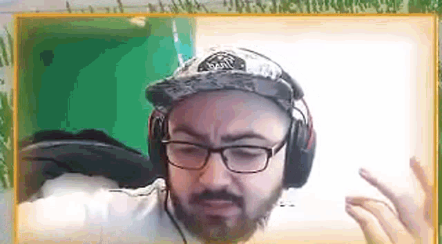 a man with a beard wearing headphones and a hat is making a funny face .