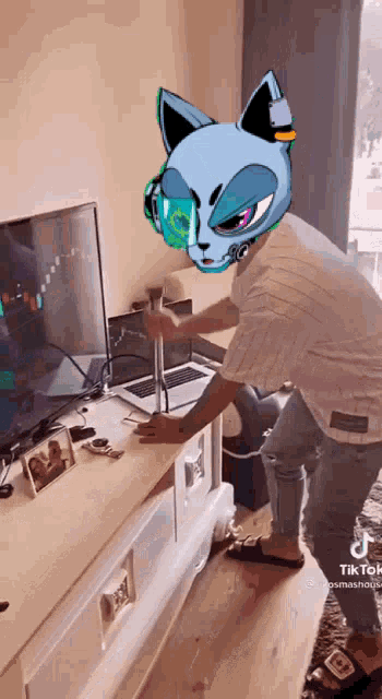 a man wearing a cat mask is standing in front of a computer