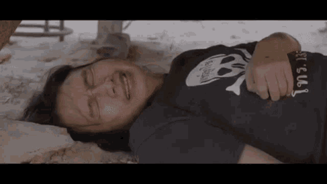 a woman is laying on the ground with her eyes closed and crying .