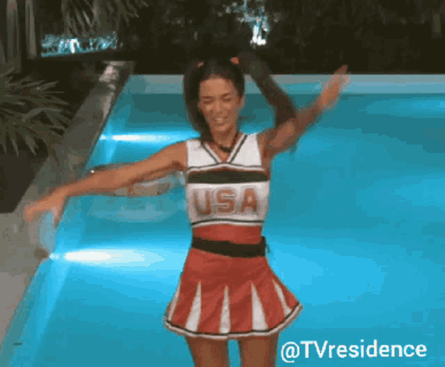 a woman in a cheerleader outfit is dancing in a pool