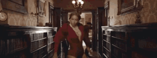 a woman in a red dress is walking down a hallway with the word tex written on the bottom .