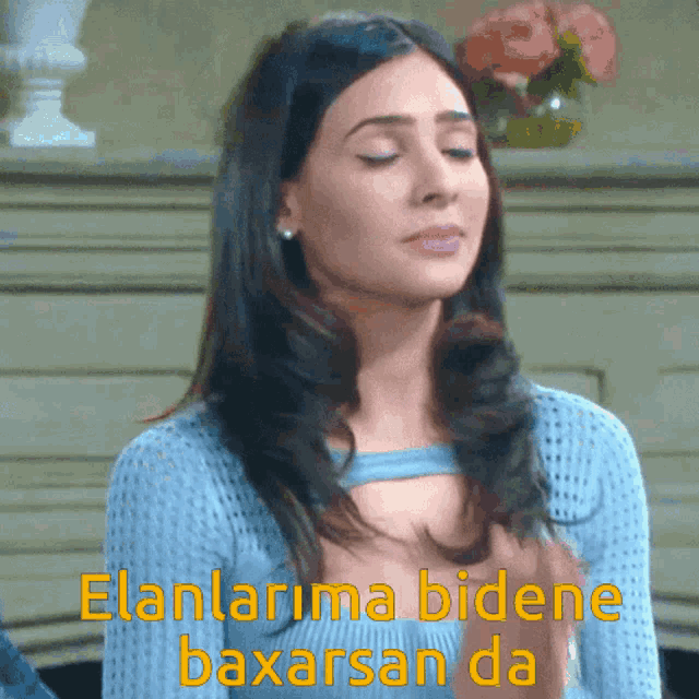 a woman in a blue sweater with the words elanlara bidene baxarsan da written above her