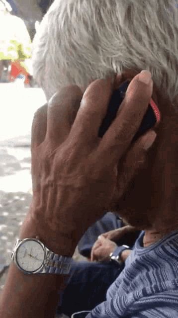 a man wearing a watch is talking on a cellphone