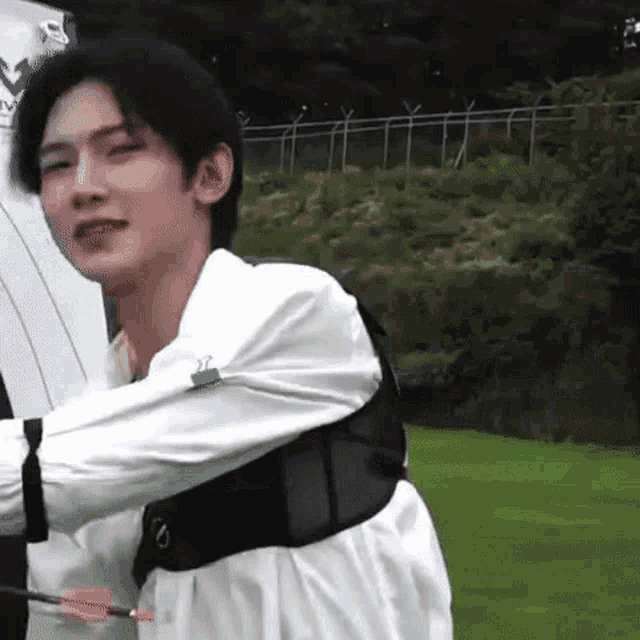 a young man is holding a bow and arrow while standing on a field .