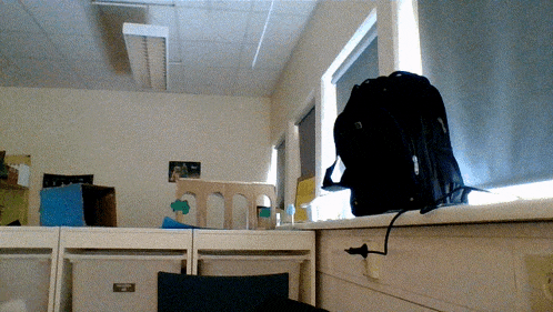 a black backpack is sitting on a window sill in a classroom
