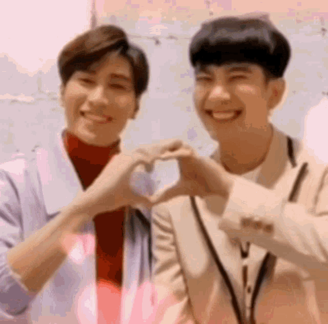 two young men are making a heart with their hands .